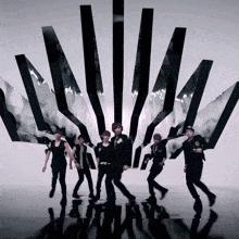 a group of young men are dancing in front of a black and white pattern