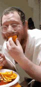 a man with glasses and a beard is eating a piece of food
