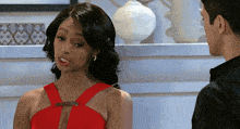 a woman in a red dress is looking at a man in a black shirt