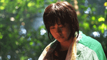 a woman is wrapped in a green and yellow blanket and the tv channel is tokyo