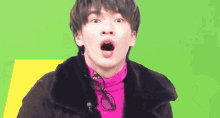 a young man wearing a pink turtleneck and glasses is making a funny face .