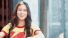 a woman in a yellow and red shirt is giving a thumbs up .
