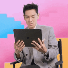 a man in a suit sits in a director 's chair holding an apple ipad