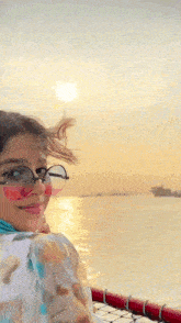 a girl wearing sunglasses and a scarf looks out over the water