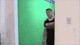 a man in a black shirt is standing in front of a green screen
