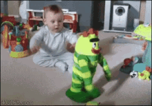 a baby is playing with a stuffed toy that looks like a frog and says 4gifs.com on the bottom