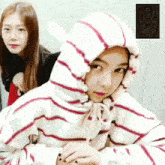 a girl wearing a striped sweatshirt with a hood is standing next to another girl
