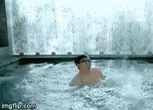 a man is swimming in a hot tub without a shirt on