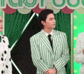 a man in a green and white striped suit and tie is standing next to two women .