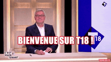 a man sitting at a desk with the words bienvenue sur t18 written on the screen behind him