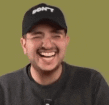 a man wearing a hat and glasses is laughing and smiling .