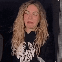 a blonde woman is making a funny face with her eyes closed .