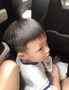 a little boy is sitting in a car holding a thermometer that says oto on it
