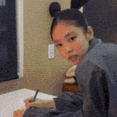 a woman is sitting at a desk with a pen in her hand .