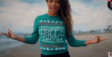 a woman wearing a sweater that says happy holly days on it
