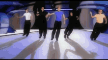 a group of men are dancing on a stage with their shadows on the floor .