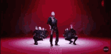 a man is dancing in front of a group of dancers on a red background .