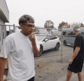 a man in a white t-shirt smoking a cigarette