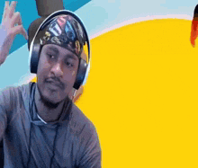 a man wearing headphones and a bandana is making a peace sign .