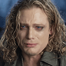 a man with long blonde hair and blue eyes is making a funny face