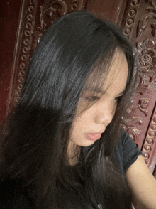 a girl with long black hair is looking down at something