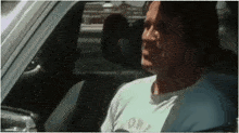 a man wearing a white shirt with the word corp on it is sitting in a car