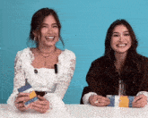 two women are sitting at a table with one holding a ticket that says ' marathon 2020 ' on it