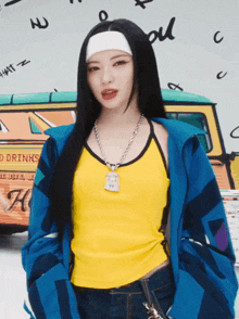 a woman wearing a yellow tank top and a blue jacket stands in front of a van that says " drinks "