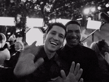 a black and white photo of two men laughing and waving