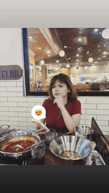 a woman sits at a table in front of a sign that says ' spicy box '