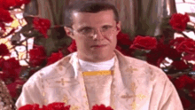 a priest is holding a bunch of red roses in front of a stained glass window .
