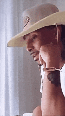 a man wearing a cowboy hat has a watch on his wrist that says peboo