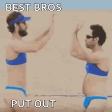 two men in bikinis are holding hands on a beach .