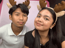 a man and a woman wearing reindeer antlers pose for a photo