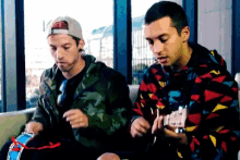 a man playing a guitar while another man looks on