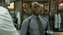 a man in a blue shirt and tie is talking to another man in a room .