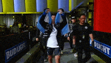 a man holding a flag walks through a bud light fence