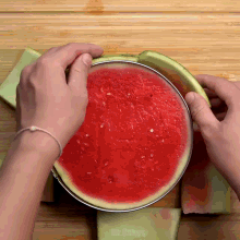 a person is cutting a watermelon on a wooden table with the words mr.cakes visible in the corner
