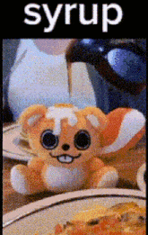 a stuffed animal is sitting in front of a plate of food with the word syrup above it