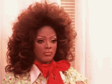 a woman with a red bow on her neck is wearing a wig and a shirt .