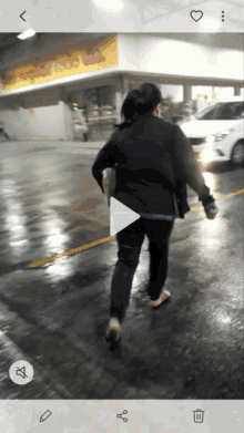 a woman is walking down a wet street in front of a store with a yellow sign that says ' chicken ' on it