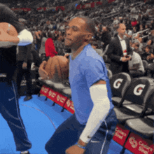 a man in a blue shirt is holding a basketball in front of a gatorade advertisement
