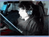 a man wearing headphones and glasses is sitting in front of a computer monitor .