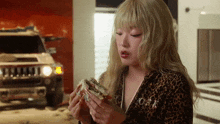 a woman wearing a leopard print top is eating a sandwich