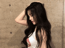 a woman with long black hair is wearing a white tank top with the letter a on it