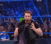 a man with a beard is standing in a wrestling ring with his mouth open in front of a crowd .