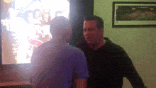 two men are standing in front of a large screen with a picture of a group of people on it