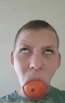 a young man with an orange in his mouth making a funny face