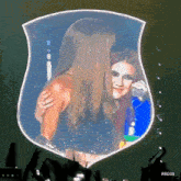 two women are hugging in front of a shield that says rbd3d on the bottom