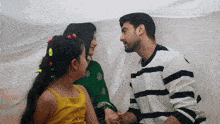 a man and woman holding hands with a little girl behind them